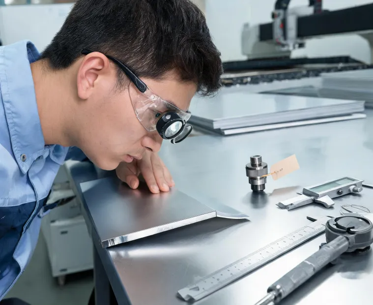 Laser cutting engineer inspecting a cut edge and nozzle setup